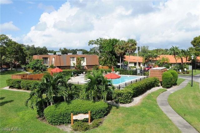 view of property's community with a lawn, fence, and a pool