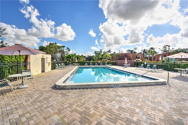 pool with a patio area and fence