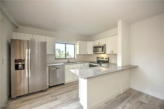 kitchen featuring appliances with stainless steel finishes, white cabinetry, and a sink