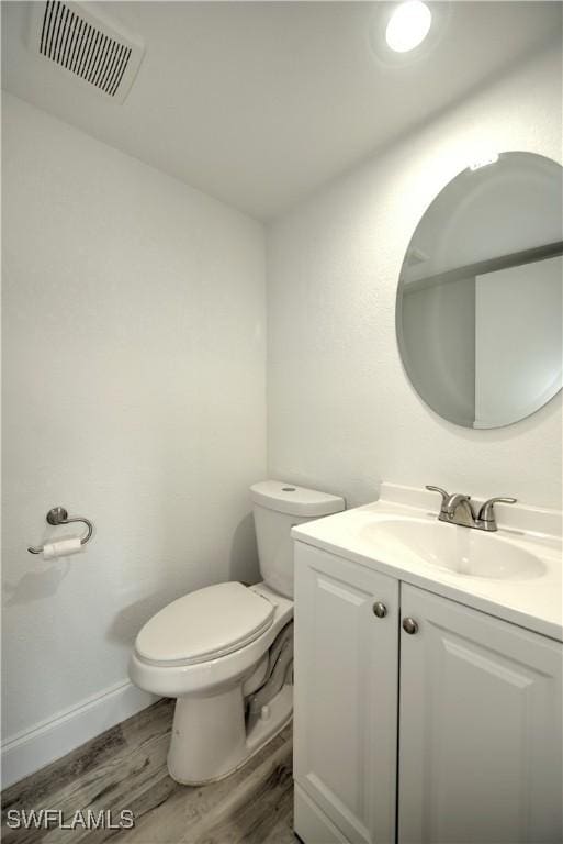 bathroom with baseboards, visible vents, toilet, wood finished floors, and vanity