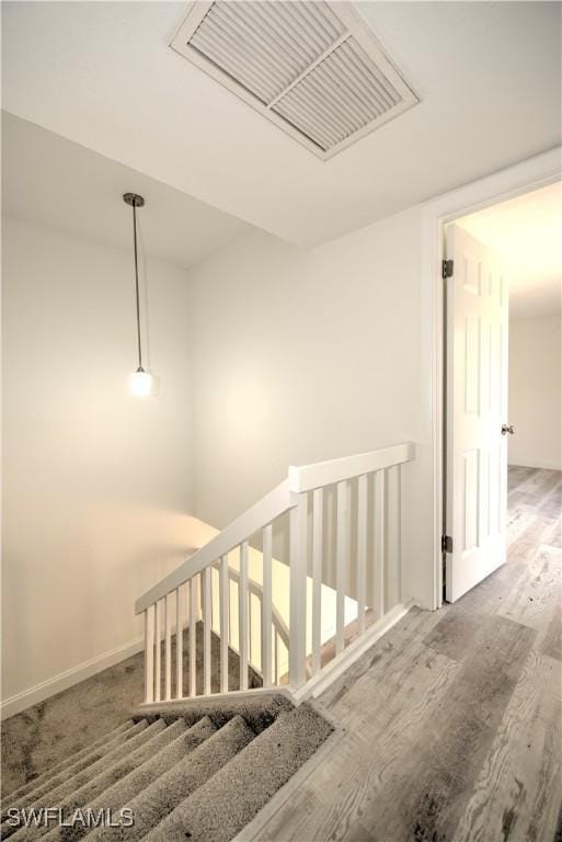 corridor featuring an upstairs landing, wood finished floors, and visible vents