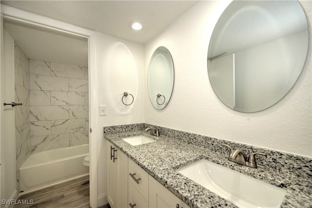 full bathroom featuring double vanity, wood finished floors, a sink, and toilet