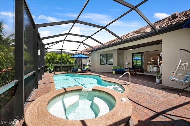 view of pool featuring a patio area, a pool with connected hot tub, and glass enclosure