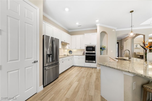 kitchen with decorative light fixtures, stainless steel appliances, white cabinetry, a sink, and light stone countertops