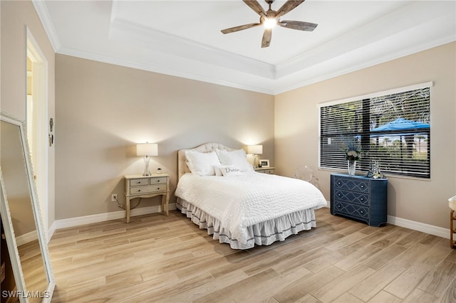 bedroom with baseboards, crown molding, a raised ceiling, and light wood-style floors