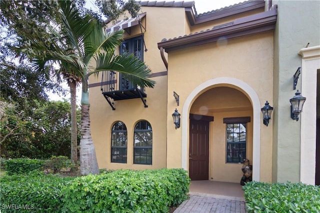 view of exterior entry featuring a tile roof and stucco siding