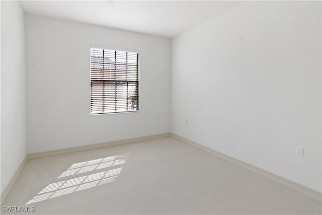 empty room featuring light colored carpet and baseboards