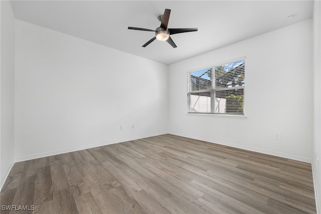 spare room with ceiling fan, light wood finished floors, and baseboards