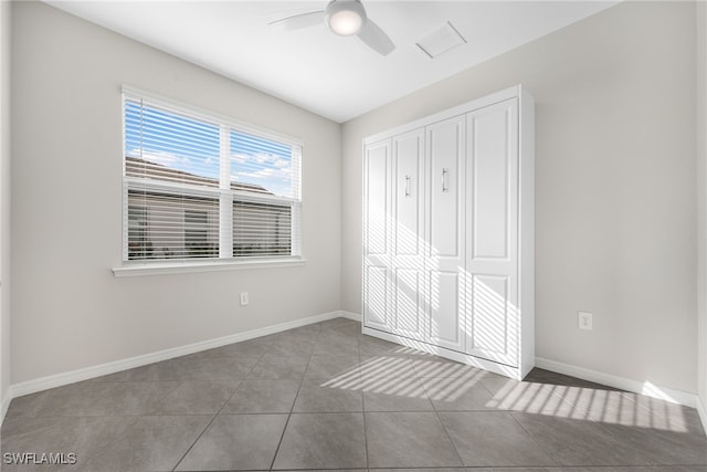 unfurnished bedroom with a closet, visible vents, a ceiling fan, tile patterned flooring, and baseboards