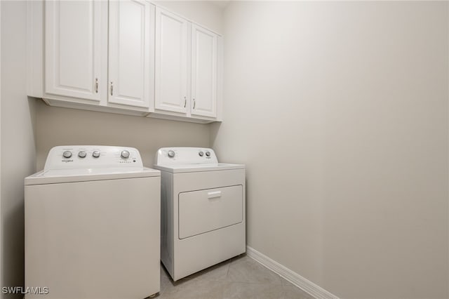 washroom featuring cabinet space, light tile patterned flooring, baseboards, and washing machine and clothes dryer