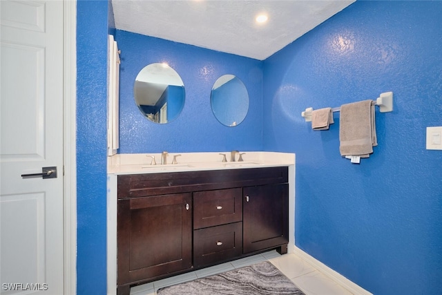 full bathroom featuring double vanity, tile patterned flooring, baseboards, and a sink