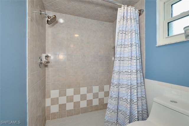 full bathroom featuring a tile shower and toilet