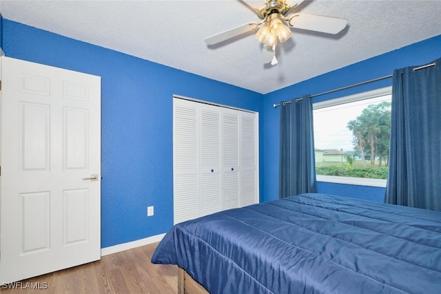 bedroom featuring ceiling fan, a textured ceiling, wood finished floors, baseboards, and a closet