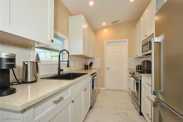 kitchen featuring marble finish floor, appliances with stainless steel finishes, a sink, and white cabinets