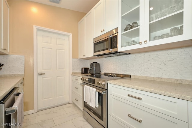 kitchen with stainless steel appliances, white cabinetry, marble finish floor, light countertops, and glass insert cabinets