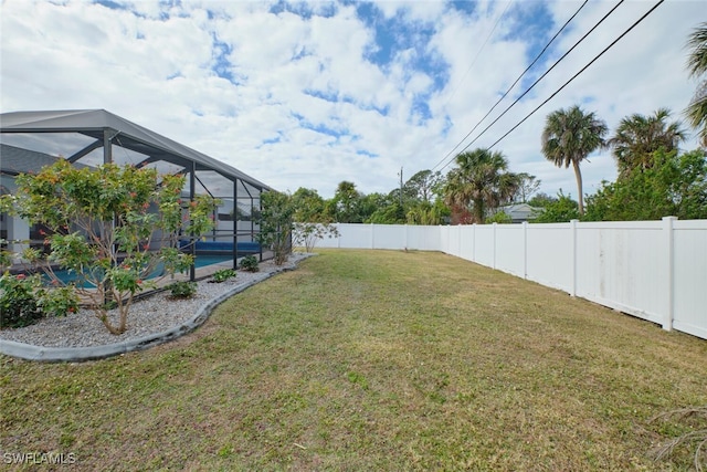 view of yard featuring glass enclosure, a fenced backyard, and an outdoor pool