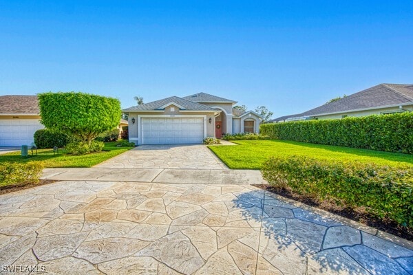 view of front of home featuring driveway, a front lawn, an attached garage, and stucco siding