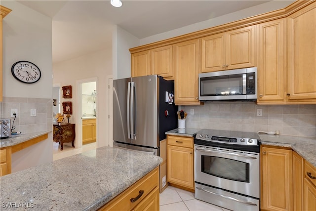 kitchen featuring stainless steel appliances, light stone counters, and backsplash