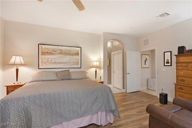 bedroom with ceiling fan, visible vents, arched walkways, and wood finished floors