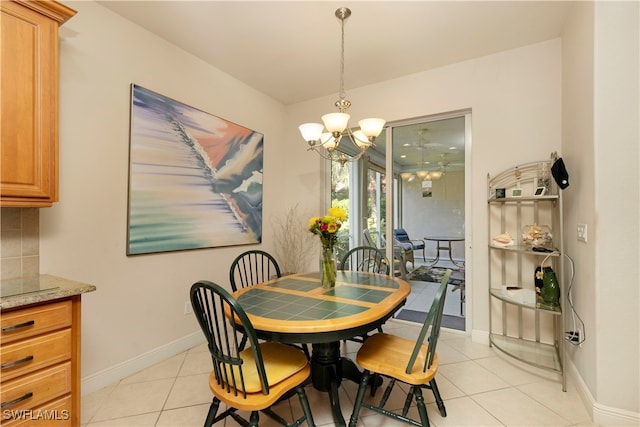 dining space with light tile patterned flooring, a notable chandelier, and baseboards