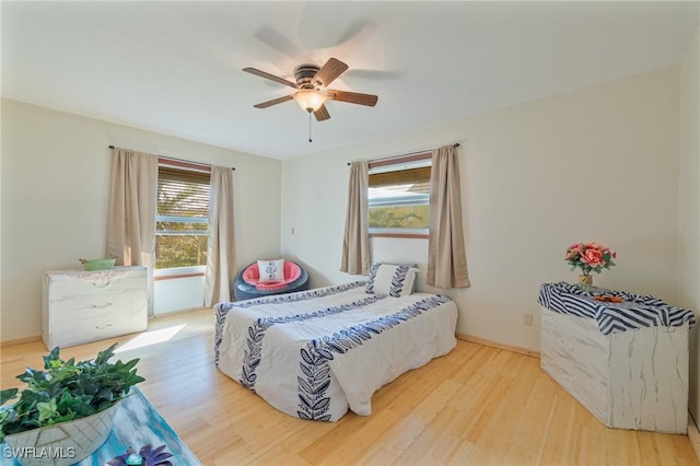 bedroom featuring ceiling fan, light wood finished floors, and baseboards