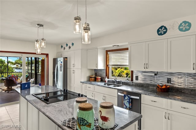 kitchen with appliances with stainless steel finishes, dark stone countertops, a sink, white cabinetry, and backsplash