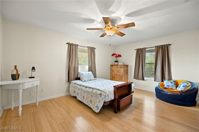 bedroom with light wood-style floors, multiple windows, and baseboards