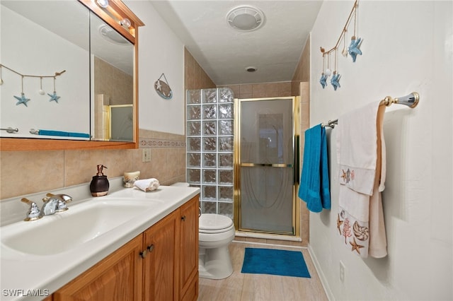 full bath with toilet, vanity, visible vents, tile walls, and a shower stall