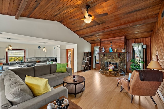 living area featuring a fireplace, lofted ceiling, light wood-style floors, wooden walls, and wooden ceiling