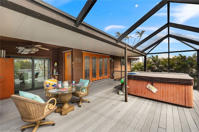 wooden terrace featuring glass enclosure, a hot tub, ceiling fan, and outdoor dining space