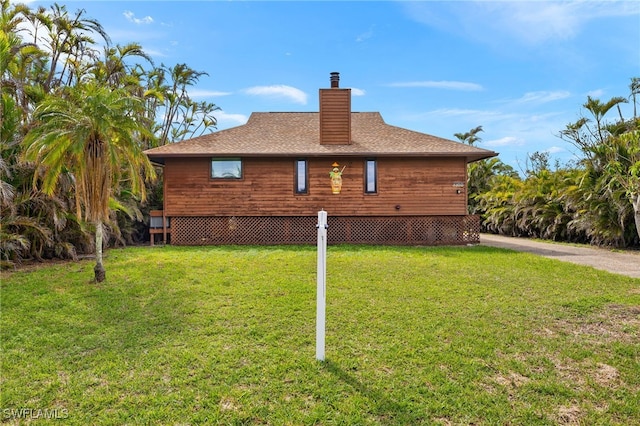 view of home's exterior with a shingled roof, a chimney, and a yard