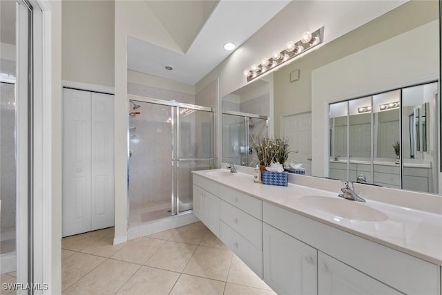 bathroom featuring double vanity, a closet, a stall shower, a sink, and tile patterned floors