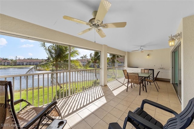 sunroom / solarium with a ceiling fan, a water view, and a sink