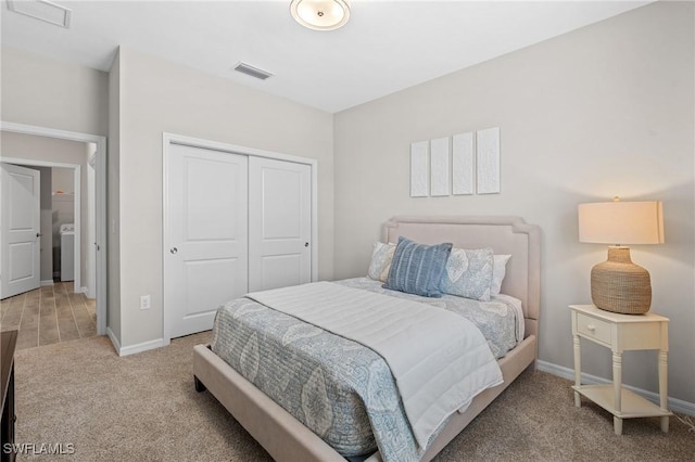 bedroom featuring a closet, washer / clothes dryer, visible vents, carpet flooring, and baseboards