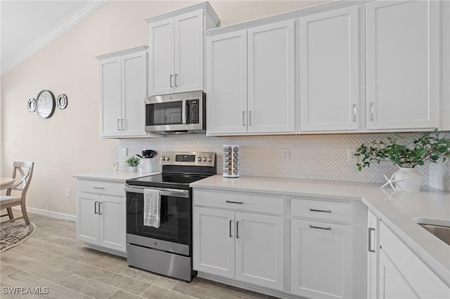 kitchen with crown molding, light countertops, decorative backsplash, appliances with stainless steel finishes, and white cabinetry