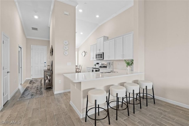 kitchen featuring stainless steel appliances, white cabinets, light countertops, and a peninsula