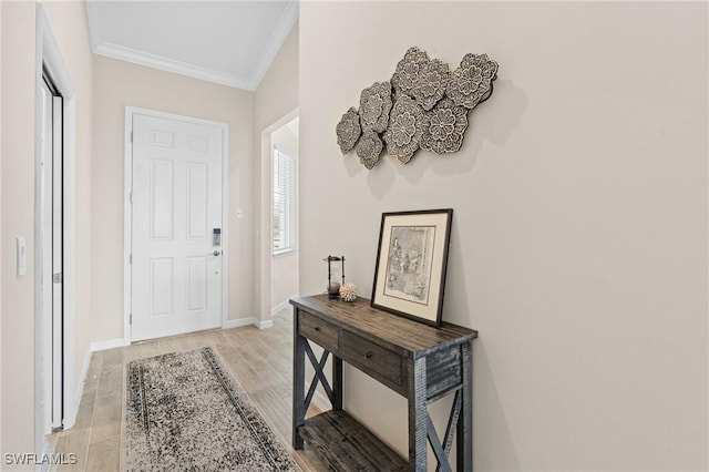 foyer with crown molding, light wood-style flooring, and baseboards