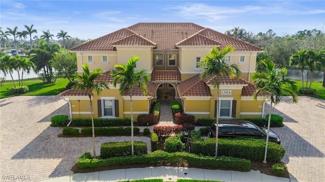 mediterranean / spanish-style home with decorative driveway, a tile roof, and stucco siding