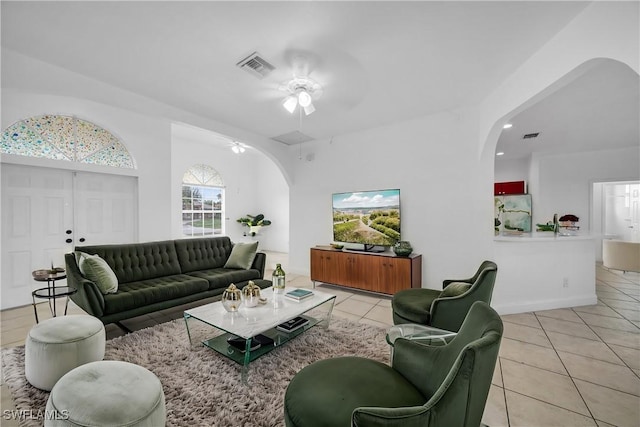 living room featuring arched walkways, light tile patterned floors, and visible vents