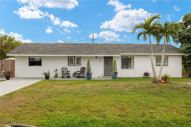 ranch-style home featuring a front lawn, a shingled roof, fence, and stucco siding