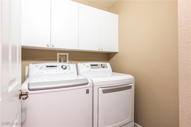 clothes washing area with washer and clothes dryer and cabinet space