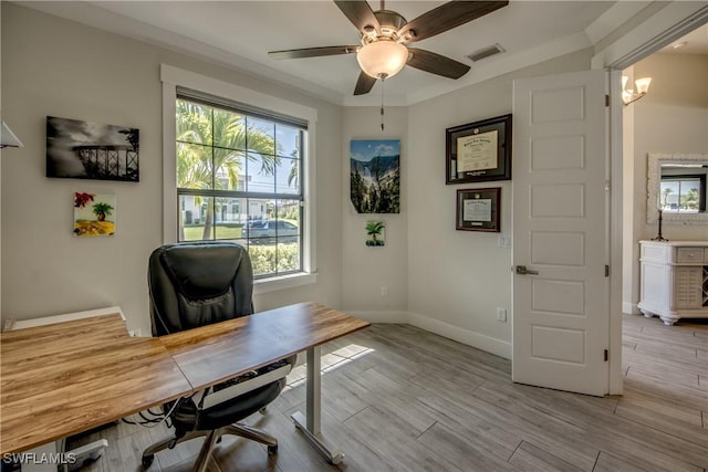 office space with baseboards, light wood-style floors, visible vents, and ceiling fan with notable chandelier