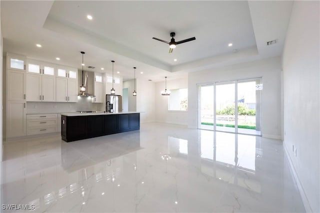 kitchen featuring a large island, a raised ceiling, light countertops, white cabinets, and stainless steel fridge with ice dispenser