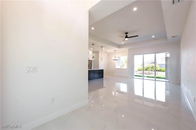 empty room with ceiling fan, recessed lighting, baseboards, marble finish floor, and a tray ceiling