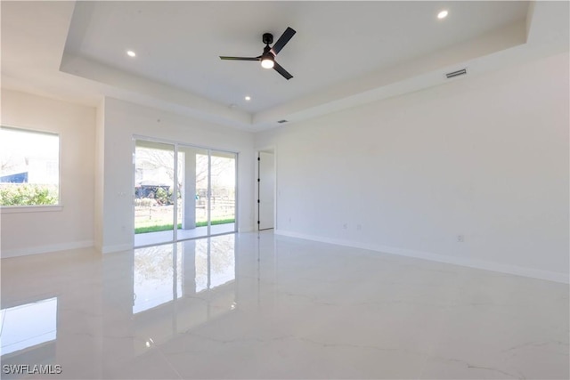 empty room featuring recessed lighting, a ceiling fan, baseboards, visible vents, and a tray ceiling