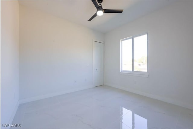 empty room featuring ceiling fan and baseboards