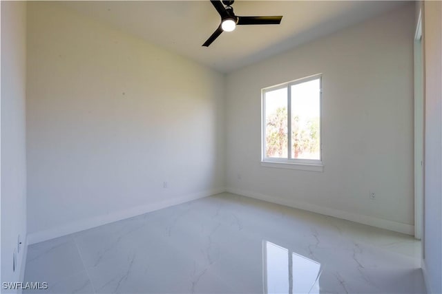 spare room with marble finish floor, baseboards, and a ceiling fan