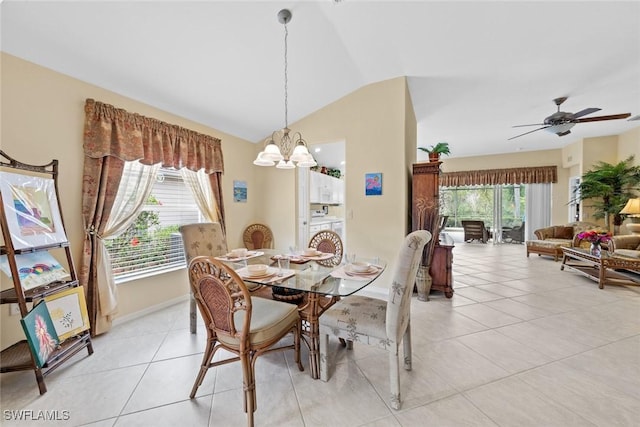 dining space with lofted ceiling, ceiling fan with notable chandelier, a wealth of natural light, and light tile patterned flooring