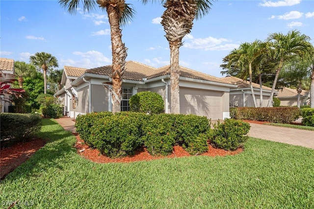 view of front of property featuring a garage, a front yard, a tile roof, and stucco siding