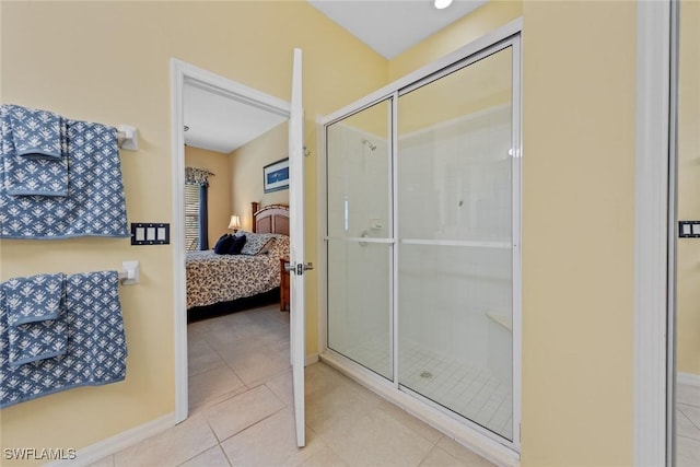 bathroom featuring tile patterned flooring, baseboards, connected bathroom, and a shower with shower door